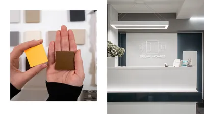Belva Homes material swatches in a hand, beside the logo on a reception wall